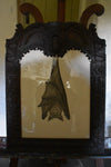 A giant Ceredigion greater horseshoe bat, hanging from an English 17th century hand-carved oak frame